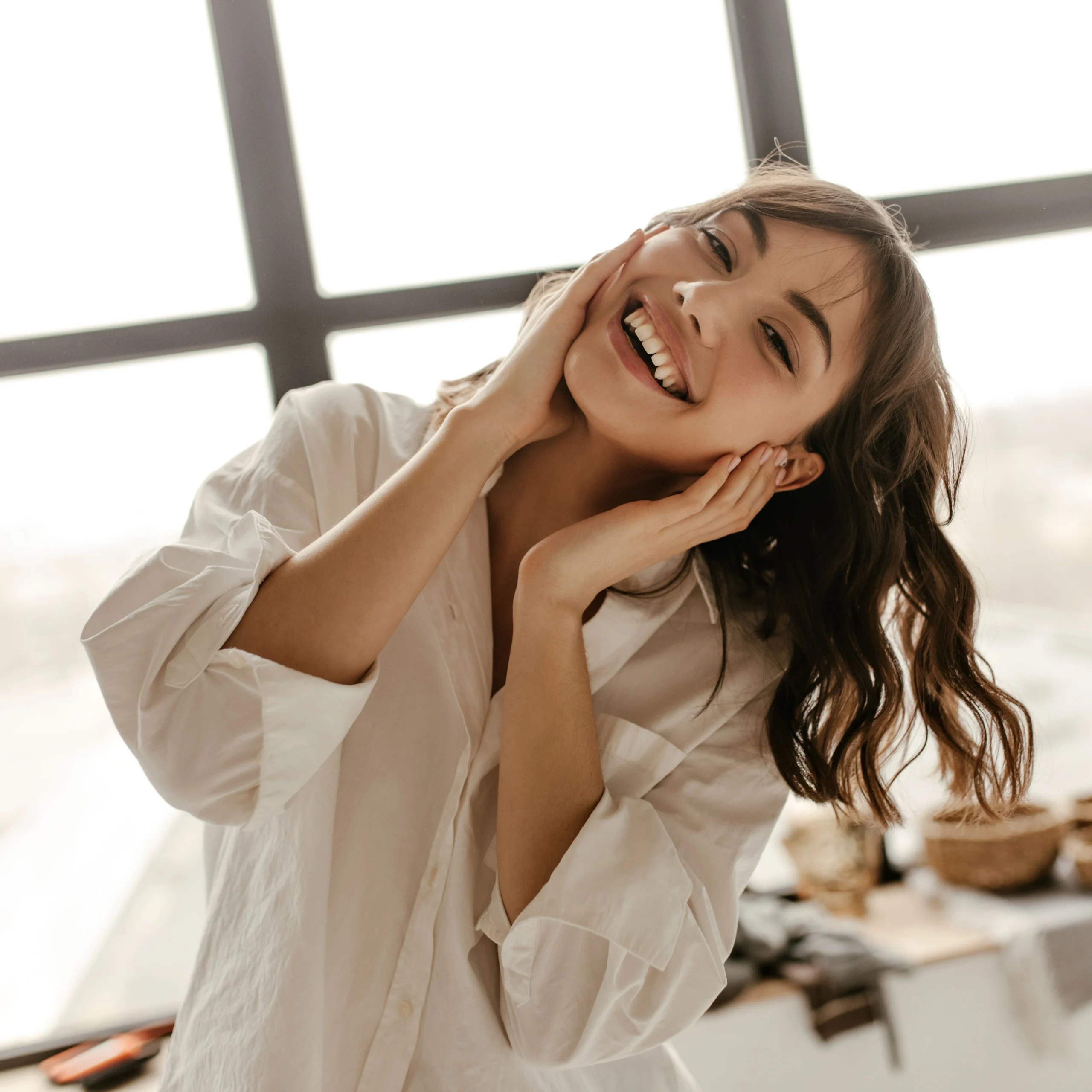 woman holding face with head tilted smiling and laughing